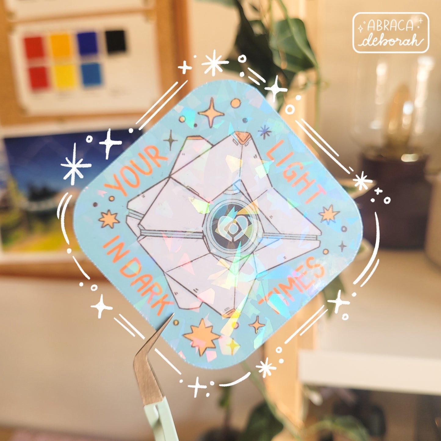 Holographic sticker of a diamond shaped machine with a light core in the middle. The words "Your light in dark times" are around the design.