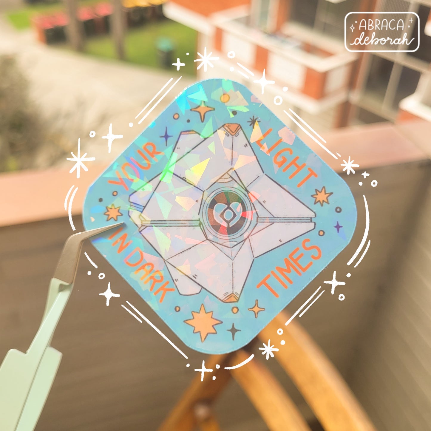 Holographic sticker of a diamond shaped machine with a light core in the middle. The words "Your light in dark times" are around the design.