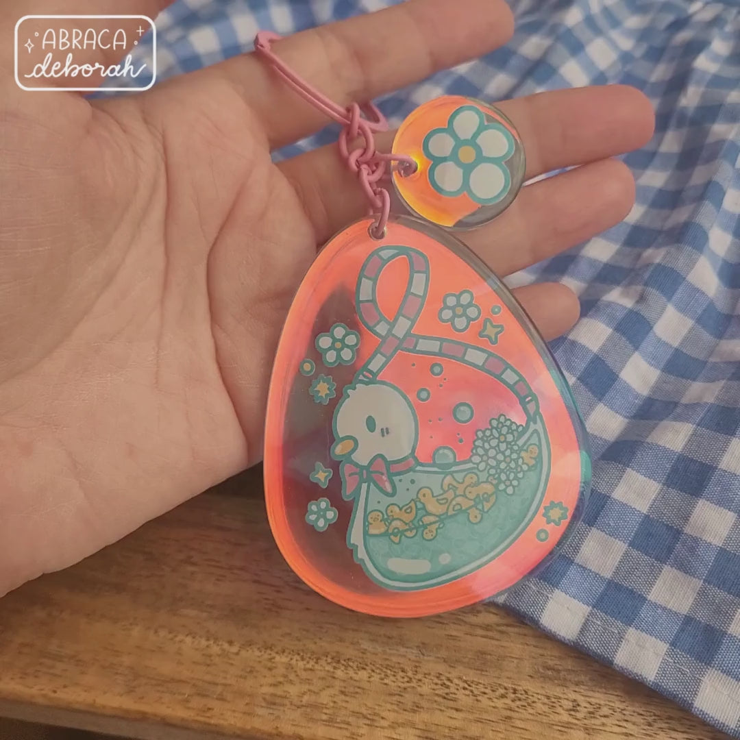 Rainbow acrylic keychain with a duck on it. Inside the big duck are small, yellow ducks in water.