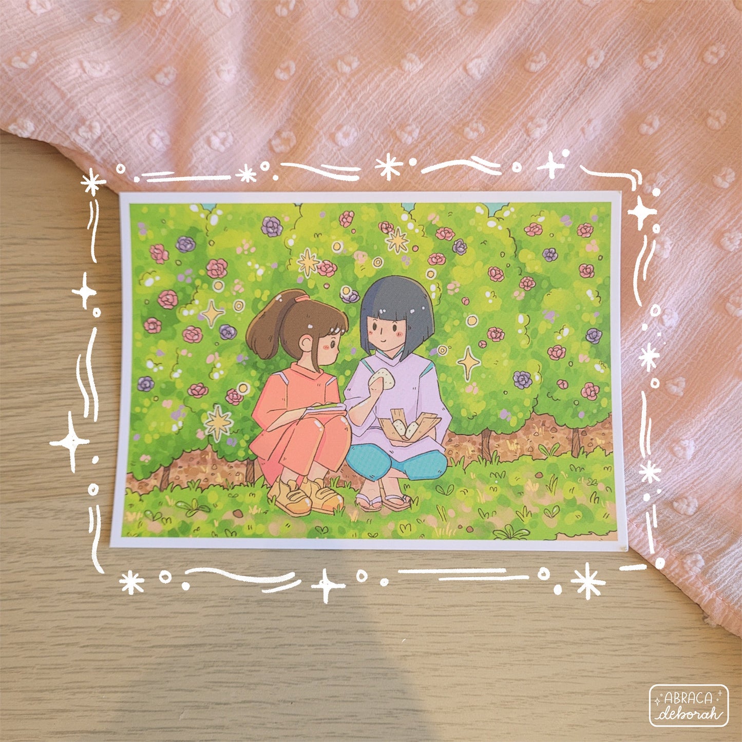 A postcard print featuring two friends sharing riceballs while hiding in the bushes.