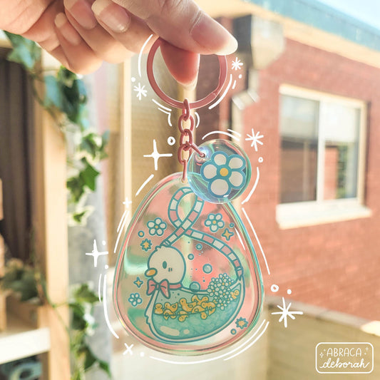 Rainbow acrylic keychain with a duck on it. Inside the big duck are small, yellow ducks in water.