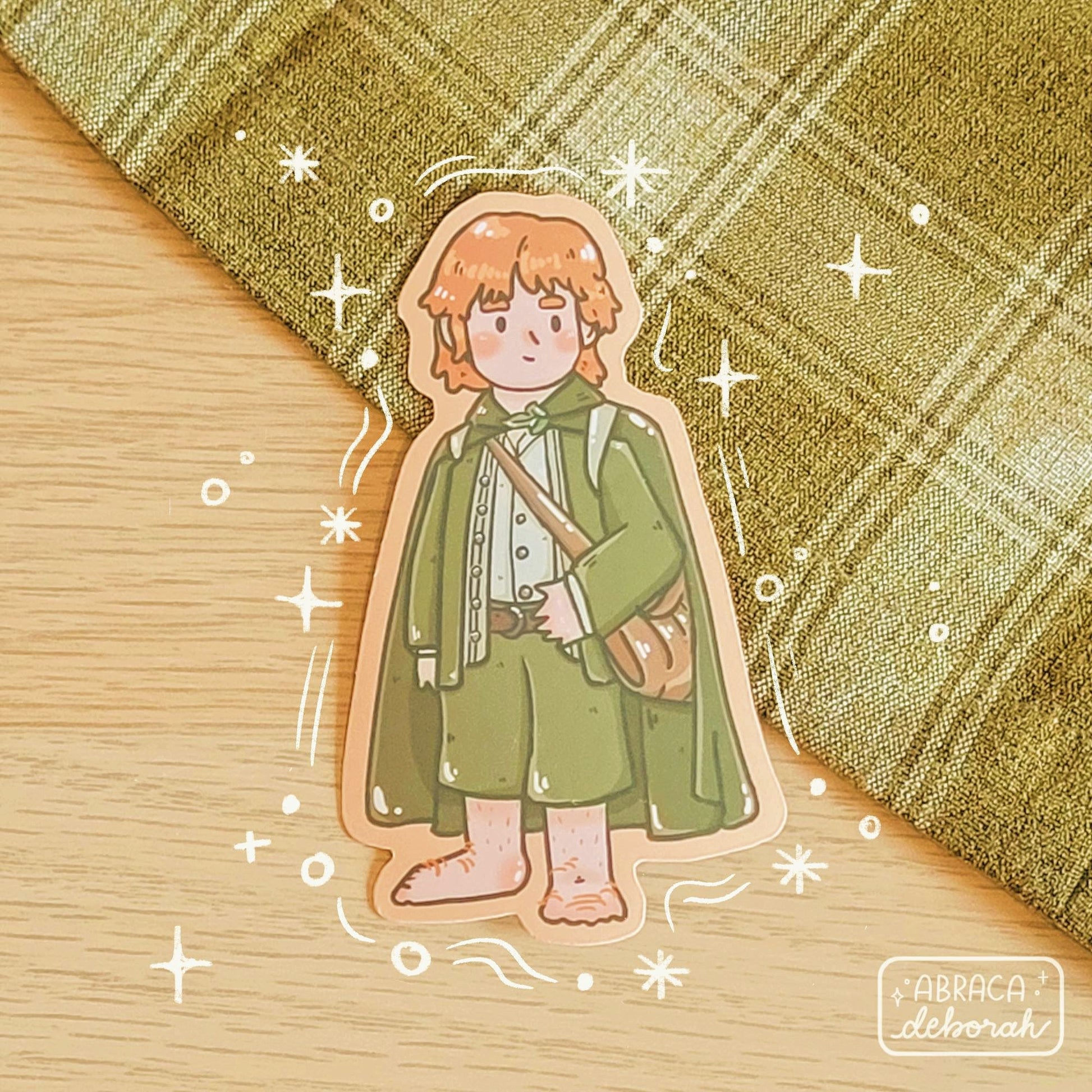 A sticker depicting an orange haired halfling wearing green, with a satchel by his side.