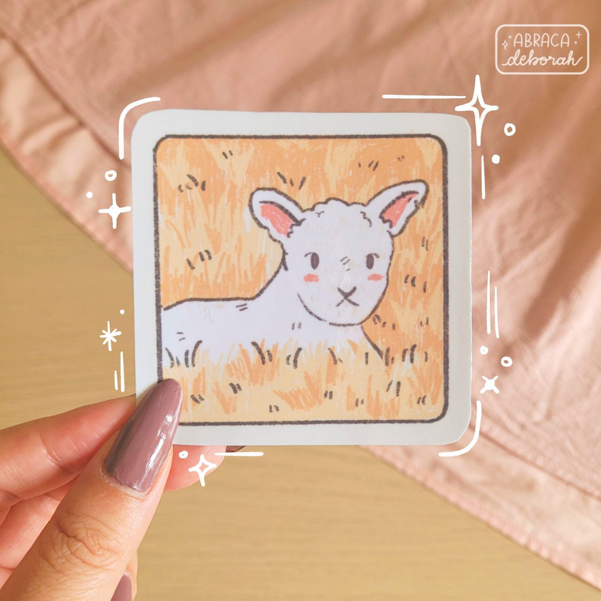 A square sticker depicting a lamb lying in a yellow field of grass.