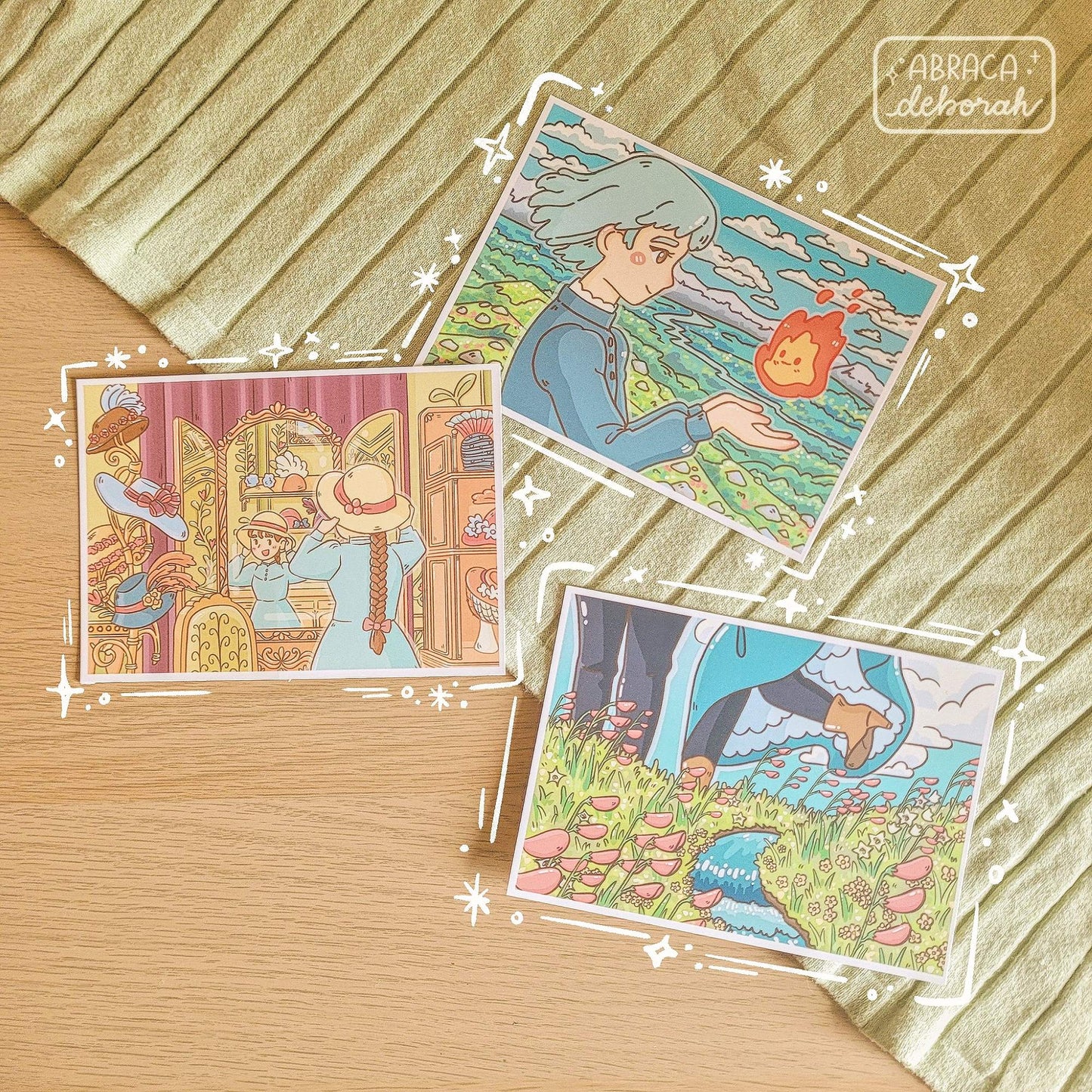 Three postcard prints depicting: a girl holding a flame, a girl trying a hat on in the mirror, and a view of two people's legs in a field of flowers.