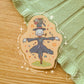 A sticker depicting a scarecrow wearing a top hat and suit.