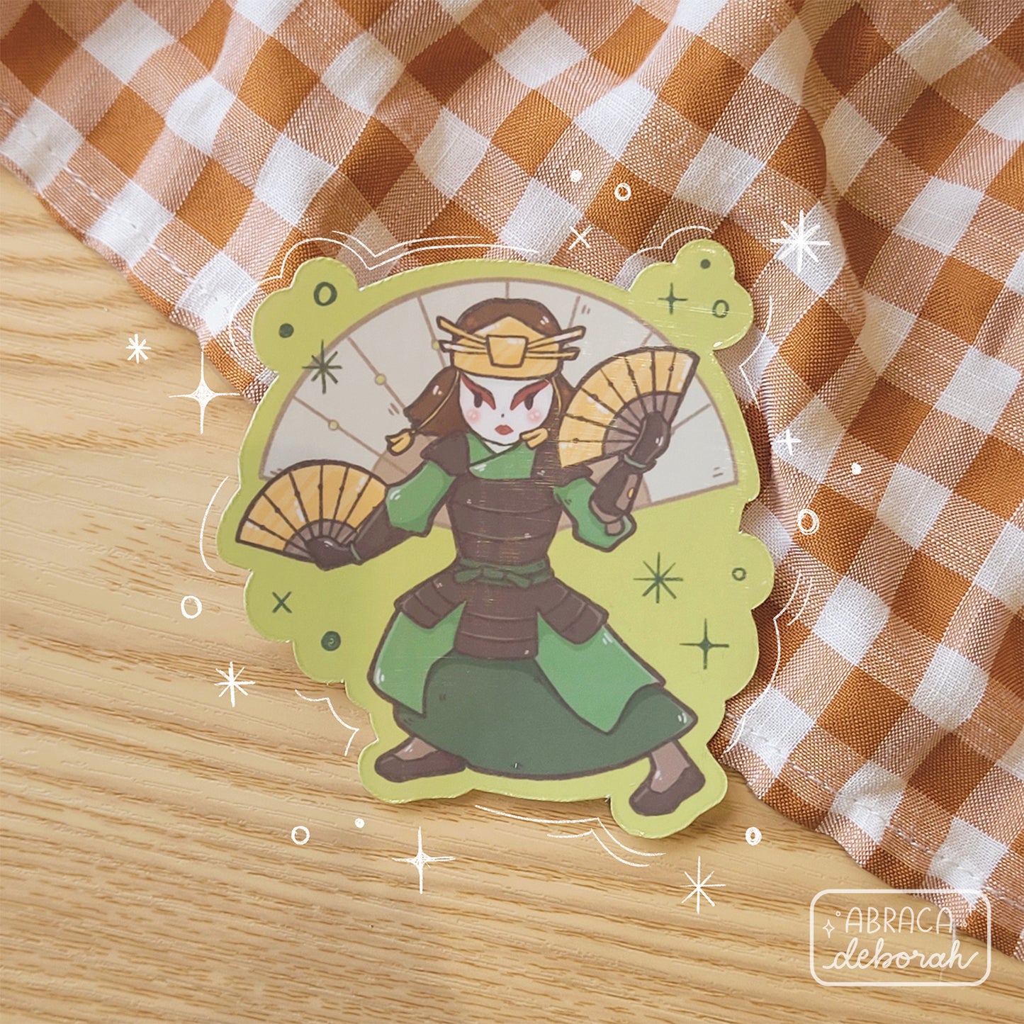 A sticker depicting a female warrior branding two metal fans.