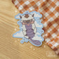 Sticker of a bison with an arrow on his head. There are clouds behind him.